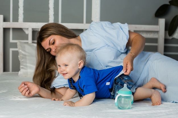 La mamma felice sta giocando sul letto con un bambino