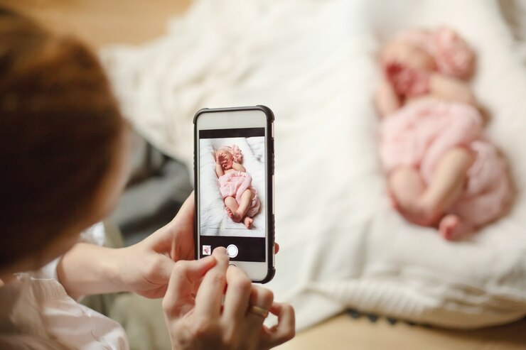 La mamma fotografa la sua neonata avvolta in una morbida coperta rosa