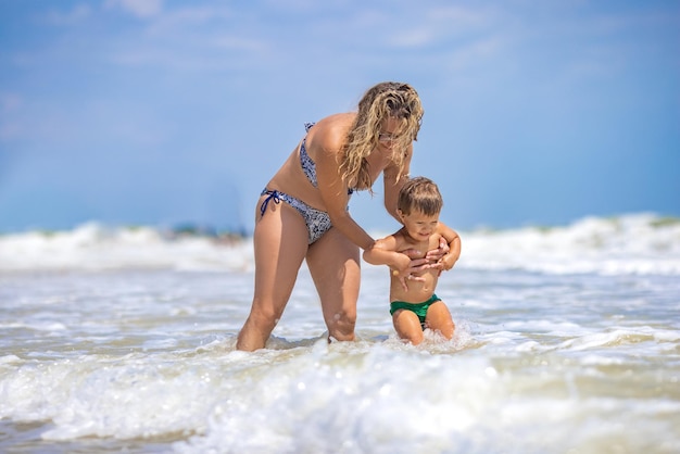 La mamma getta suo figlio al mare durante le vacanze estive sotto il caldo sole