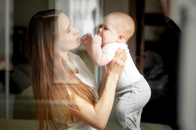 La mamma gioca con il bambino 6 mesi sul letto di casa