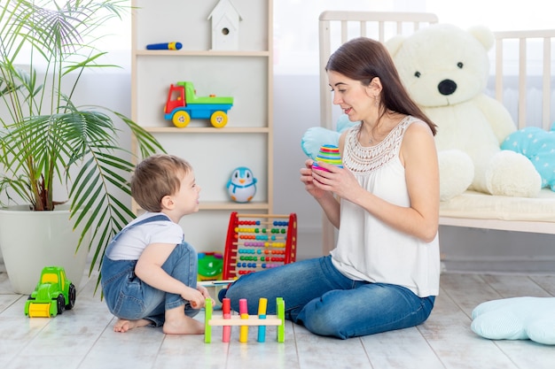 La mamma insegna al bambino a casa giocando a giocattoli educativi nella stanza dei bambini. Una famiglia felice e amorevole.