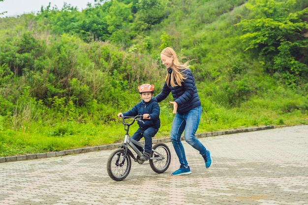 La mamma insegna al figlio ad andare in bicicletta nel parco.