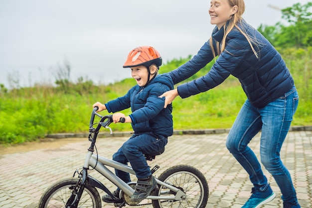 La mamma insegna al figlio ad andare in bicicletta nel parco.
