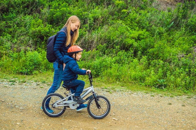 La mamma insegna al figlio ad andare in bicicletta nel parco.