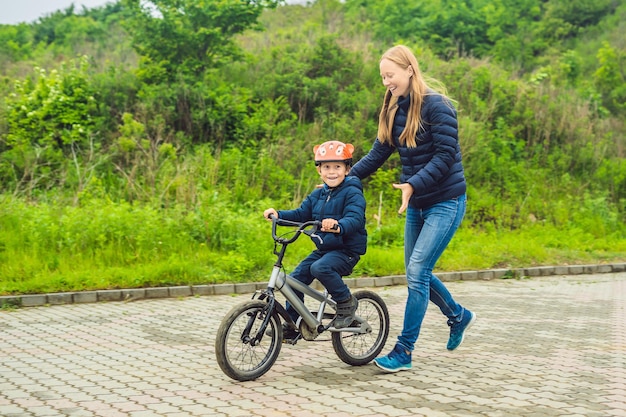 La mamma insegna al figlio ad andare in bicicletta nel parco.