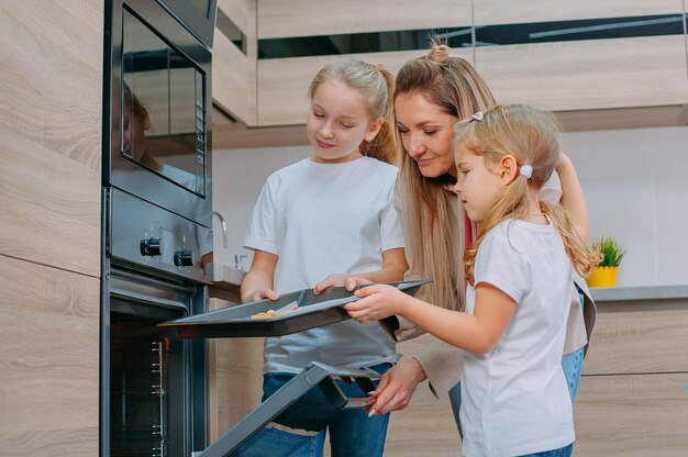 La mamma insegna alle figlie a cucinare in cucina.