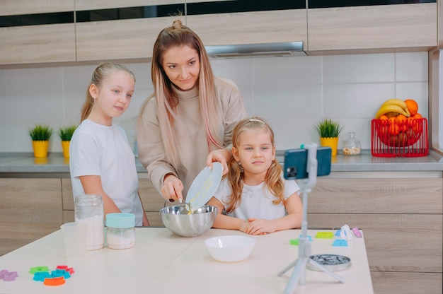 La mamma insegna alle sue figlie a cucinare la pasta in cucina.