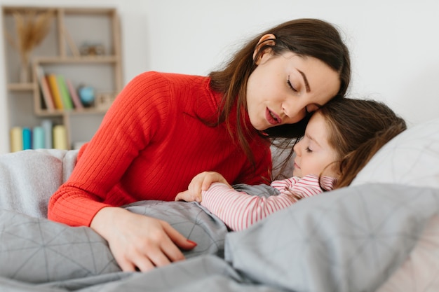 La mamma mette a dormire una piccola bambina.