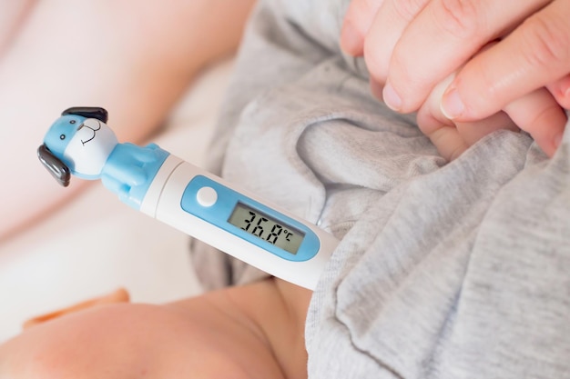 La mamma misura la temperatura del bambino Termometro sotto il braccio Prendersi cura della salute del bambino prevenzione delle malattie raffreddore influenza