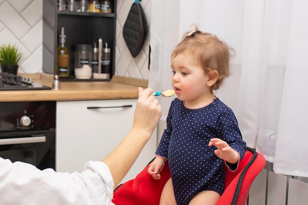 La mamma nutre la sua adorabile piccola figlia con un cucchiaio Allattando il bambino