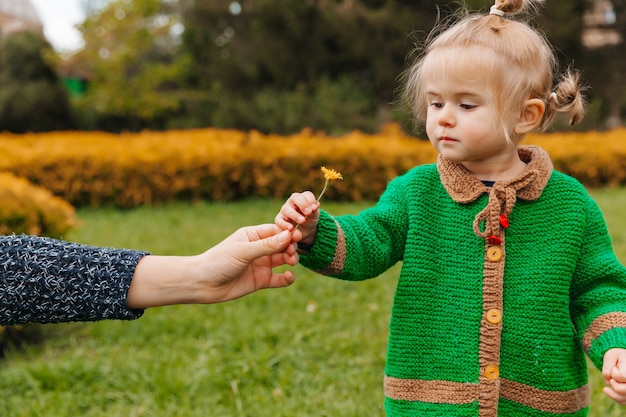 La mamma porge un fiore al bambino. bambina con un fiore nel parco.