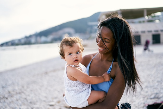 La mamma sorridente guarda la bambina nel suo ritratto di braccia