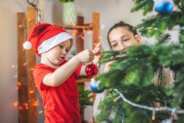 La mamma sta aiutando suo figlio a decorare l'albero di Natale