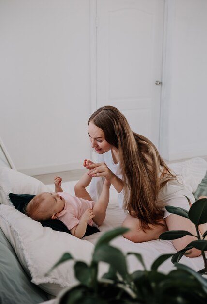 La mamma sta giocando con una bambina sul letto in camera