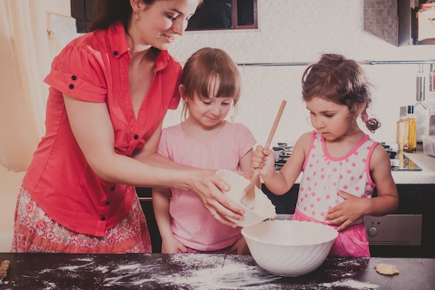 La mamma sta preparando i biscotti con i suoi bambini nella cucina di casa