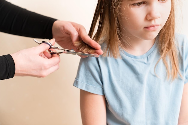 La mamma taglia i capelli bagnati di sua figlia tagliando i capelli a casa