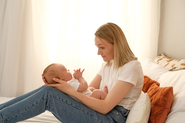 La mamma tiene in braccio un neonato sullo sfondo il sole splende dalla finestra