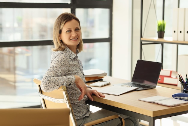 La manager siede sul posto di lavoro in ufficio e guarda la telecamera che lavora in ufficio, affari online e