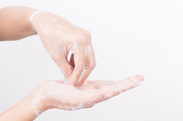 La mano asiatica della donna sta lavando con le bolle di sapone su fondo bianco