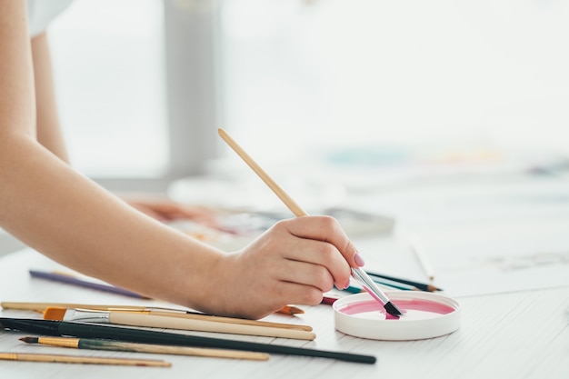 La mano che lavora con un pennello artistico e vernici