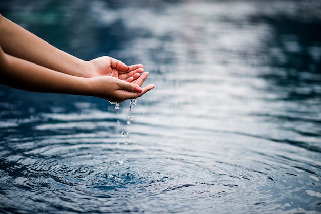 La mano che tocca l&#39;acqua blu.