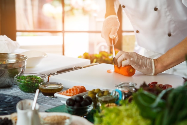 La mano con il coltello taglia la carota.