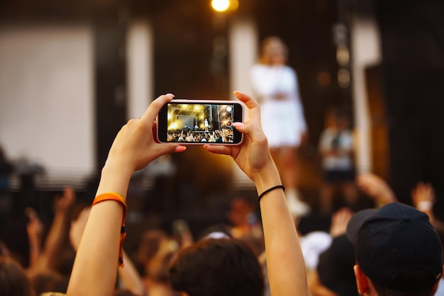 La mano con un telefono registra il festival di musica dal vivo Persone che scattano fotografie con lo smartphone