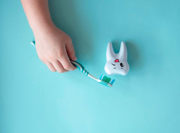 La mano dei bambini offre un grande dente sano di plastica e uno spazzolino da denti con uno spazio per testo il concetto di odontoiatria per bambini