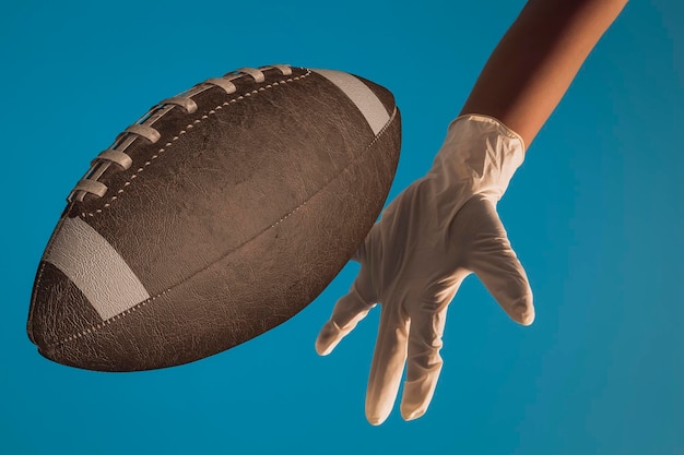 La mano del bambino con un guanto di lattice bianco, che gioca con un pallone da calcio su sfondo blu, illustrazione 3D