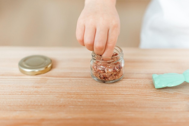 La mano del bambino prende il sale da un barattolo di vetro per salare il cibo