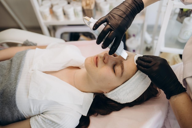 La mano del cosmetologo sta facendo il trattamento della pelle di ringiovanimento della cavitazione Trattamento del viso Cura della pelle del viso Cura della pelle di bellezza Trattamento di ringiovanimento