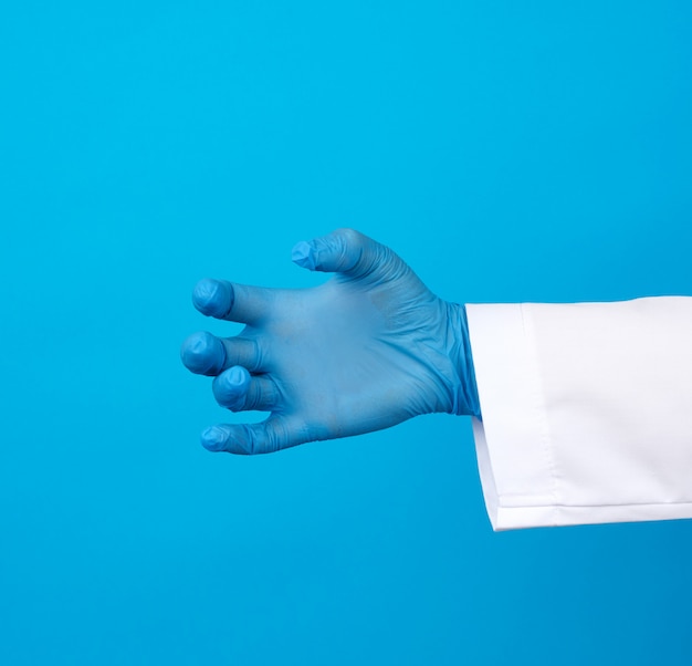 La mano del dottore indossa un guanto di gomma sterile blu che regge un oggetto