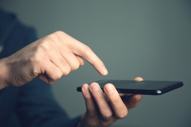 La mano del giovane che tiene telefono astuto