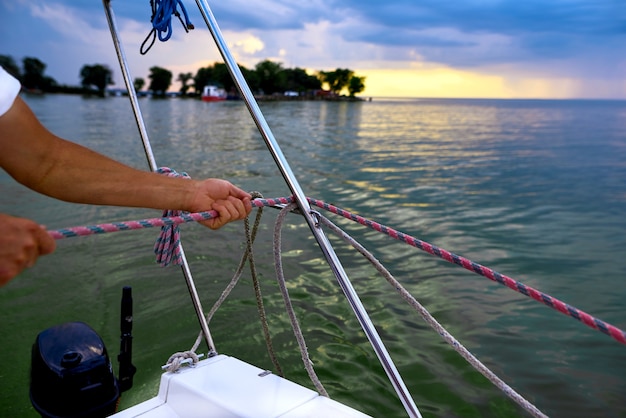 La mano del marinaio tira la corda a bordo della nave sul pittoresco paesaggio marino. profondità di campo foto.