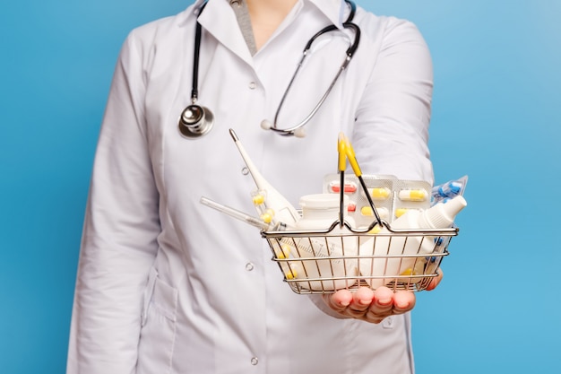 La mano del medico fornisce un carrello con varie pillole, compresse, siringhe, termometro e flaconi di medicinali