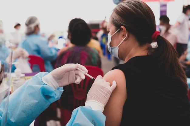 La mano del medico ha vaccinato il coronavirus covid a una donna anziana asiatica grassa in un ospedale da campo