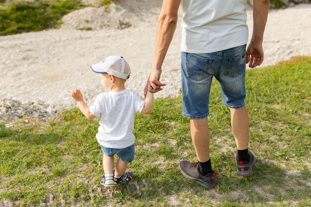 La mano del padre guida suo figlio nel concetto di famiglia di fiducia all'aperto della natura della foresta di estate