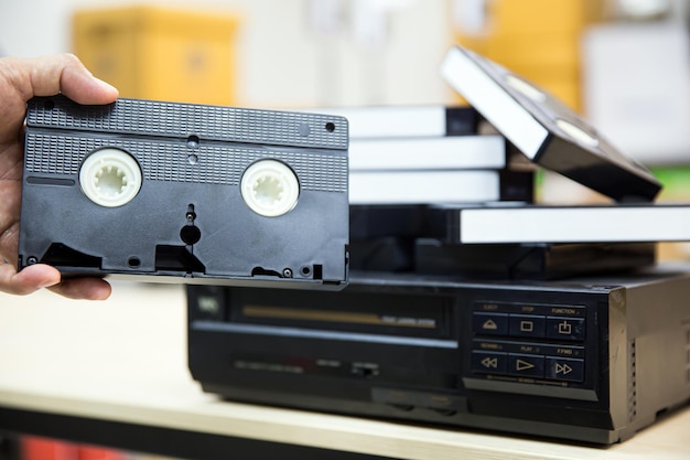 La mano del primo piano sceglie il nastro della videocassetta VHS vecchio stile retrò sul concetto di riproduzione di registrazioni video di apparecchi elettrici ed elettronici vintage dispositivo lettore multimediale vecchio stile