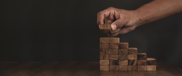 La mano del primo piano sta posizionando il blocco di legno impilato nel gradino