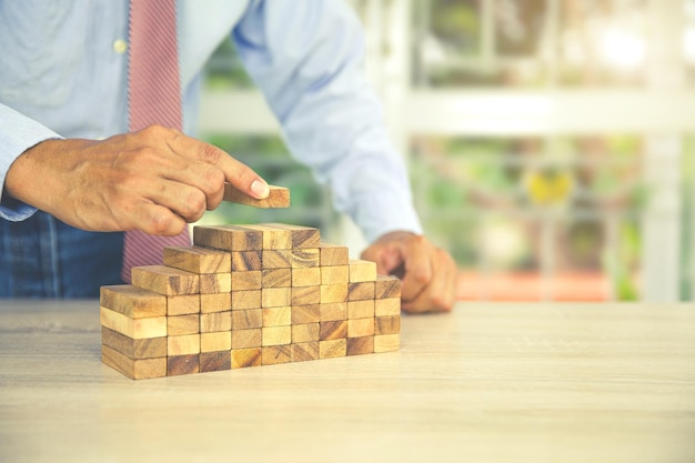 La mano del primo piano sta posizionando il blocco di legno impilato nel gradino