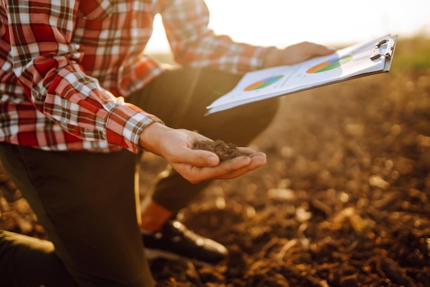 La mano dell'agricoltore esperto raccoglie il terreno e controlla la salute del suolo prima della crescita di un seme di ortaggio