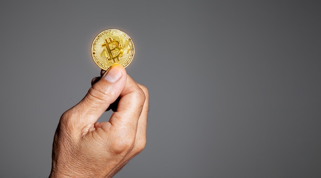 La mano dell'anziano tiene una moneta d'oro Bitcoin. Il denaro di criptovaluta Fiducia finanziaria degli anziani dopo il concetto di pensionamento.