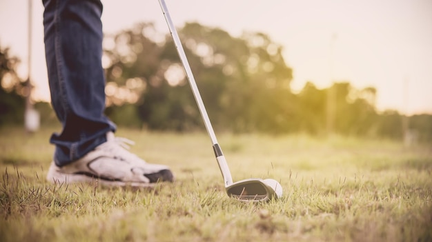 La mano dell'uomo asiatico che tiene una mazza da golf su sunsetthailand peopleGolfer gioca a golf sul campo la sera