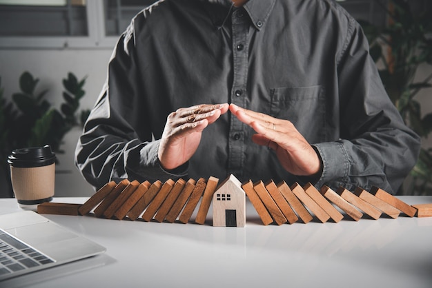 La mano dell'uomo blocca il blocco di legno da molte file che cadono blocchi di legno come il domino per il modello della casa