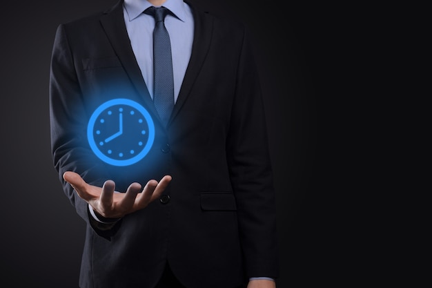 La mano dell'uomo d'affari tiene l'icona dell'orologio delle ore con la freccia. Esecuzione rapida del lavoro La gestione del tempo lavorativo e il tempo lavorativo sono concetti di denaro.