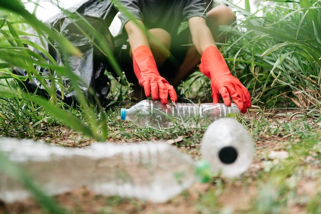 La mano dell'uomo del ragazzo prende la bottiglia di plastica nella foresta. conservazione della natura e concetto di ambiente.