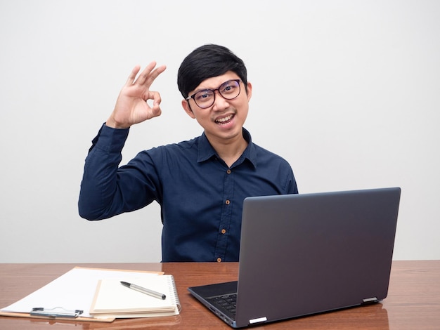 La mano dell'uomo di affari del giovane ok si siede sul fondo bianco del posto di lavoro