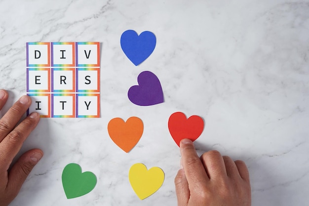 La mano dell'uomo ha posizionato piccoli cuori con i colori del movimento LGBTQ accanto alla parola diversità