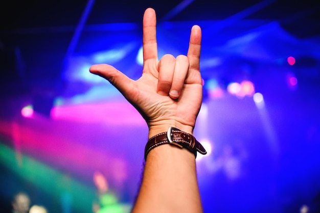 La mano dell'uomo mostra un gesto Corni sullo sfondo di un concerto musicale