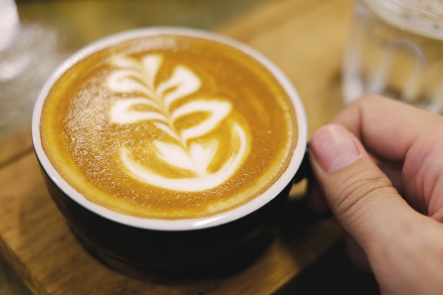 La mano dell&#39;uomo prende il caffè caldo del latte